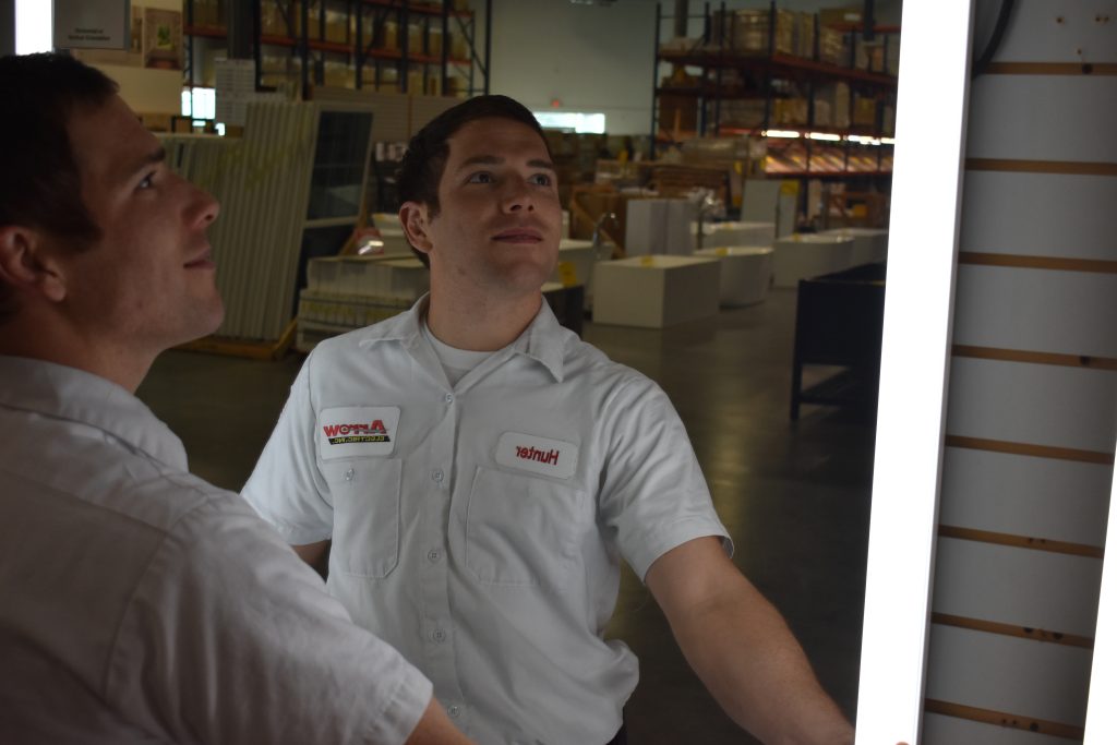 Arrow Electric employees evaluating a lighting fixture in a warehouse.